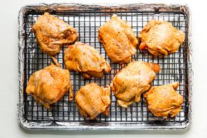 baking sheet lined with foil with bone in skin on chicken thighs seasoned with paprika, salt and pepper