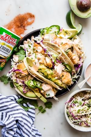 plate of spicy fish tacos topped with slaw, avocados and fresh jalapenos