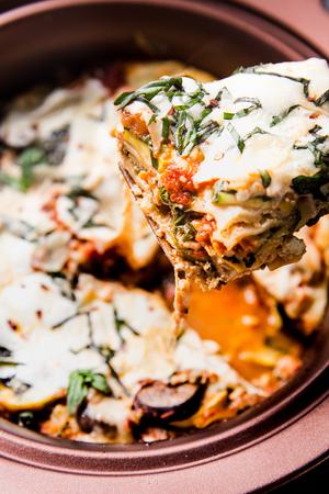 spoon scooping out a serving of finished vegetarian lasagna with basil and parmesan cheese
