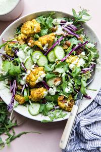 Curried Cauliflower Quinoa Salad with tahini dressing with cucumber and cabbage in a bowl with a fork