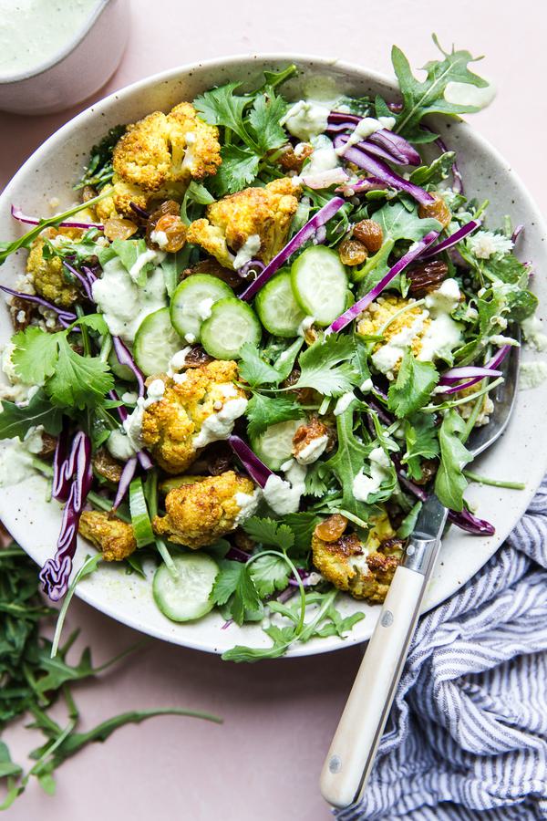 Curried Cauliflower Quinoa Salad with tahini dressing with cucumber and cabbage in a bowl with a fork