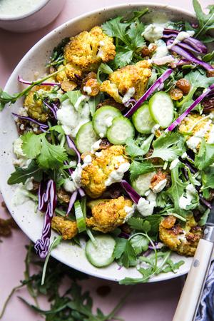 Curried Cauliflower Quinoa Salad with tahini dressing with cucumber and cabbage in a bowl with a fork