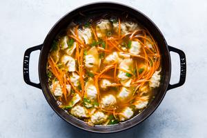 mini pot stickers in a pot with broth, carrots and green onions for dumpling soup