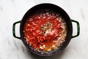 onion, pancetta, vodka, garlic, tomatoes and salt cooking in a pot to make easy vodka sauce