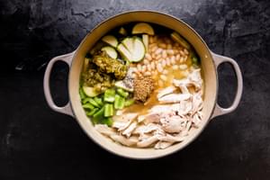 Green Chicken Enchilada Soup in a pot with beans, zucchini, bell peppers and chicken.