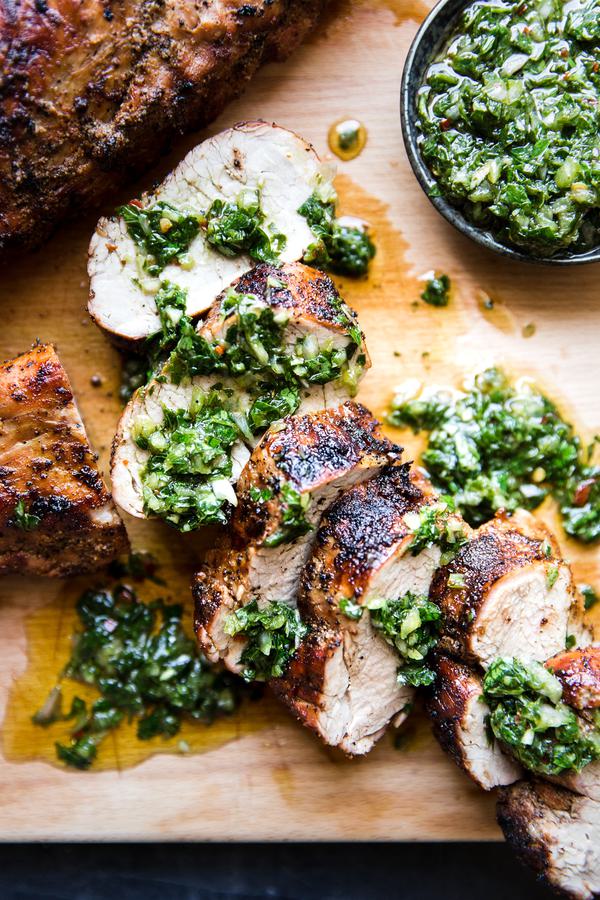 Grilled Pork Tenderloin sliced on a cutting board With Chimichurri