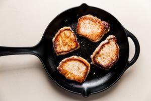 4 pork chops cooking in a cast iron skillet