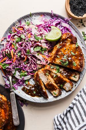 Hoisin Glazed Pork Chops on a plate with Asian coleslaw and a fork