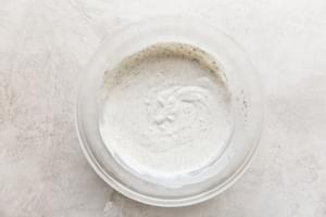 Whisking together dried herbs, sour cream, mayo, and buttermilk to create a creamy, flavorful ranch dressing from scratch.