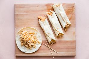 Homemade Chicken Taquitos being assembled with toothpicks on a cutting board