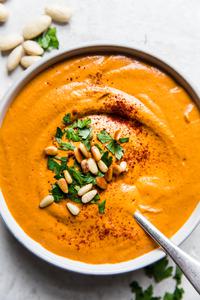 bowl of homemade romesco sauce topped with pine nuts, parsley and smoked paprika