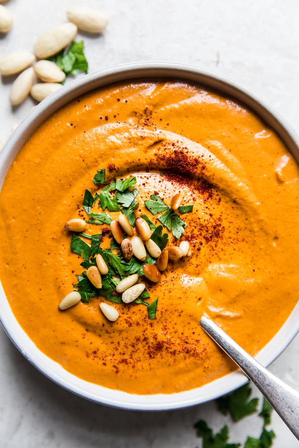 bowl of homemade romesco sauce topped with pine nuts, parsley and smoked paprika