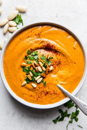bowl of homemade romesco sauce topped with pine nuts, parsley and smoked paprika