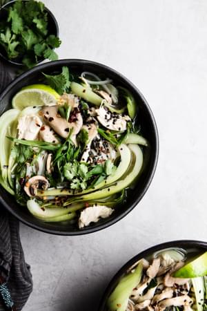 two bowls of leftover turkey soup with shallots, garlic, ginger, chicken stock, bok choy, mushrooms and rice noodles