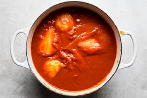 homemade spaghetti sauce cooking in a pot made with tomato sauce, crushed whole tomatoes, onions and butter