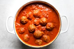 homemade pork and beef Italian meatballs simmering in a large pot filled with homemade spaghetti sauce