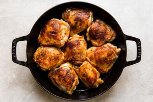 cast iron braiser with bone in skin on chicken thighs that are browned