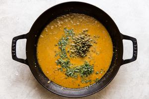 chicken stock, herb and butter sauce pan in a black skillet with capers and fresh herbs