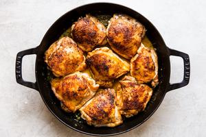 crispy chicken thighs in black cast iron skillet with sauce pan