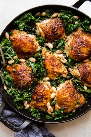 one pot braised chicken and kale with white beans in a cast iron skillet