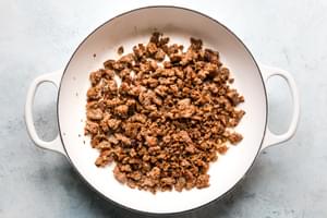 large white skillet of browned Italian sausage for chicken and stuffing casserole with sausage