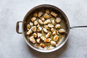 Chicken breast pieces browning in a pan.