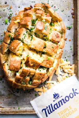 pull apart cheese bread on a silver baking sheet with Tillamook Cheese shreds