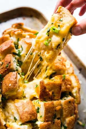 hand pulling piece of bread out cheese pull apart bread