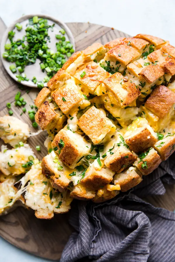 cheesy pull apart cheese bread topped with green onions on a cutting board