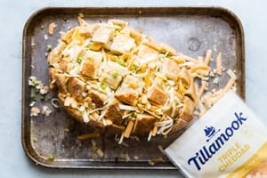 crusty bread loaf sliced on a sheet pan stuffed with triple cheddar cheese shreds