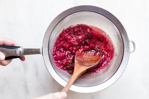 straining rhubarb sauce with a wooden spoon