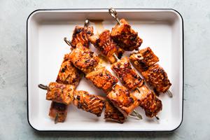 four crispy salmon bite kebabs on a white metal tray