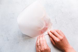hand folding parchment paper in half over salmon
