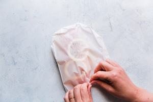 hands folding the corner folds of parchment paper pouch