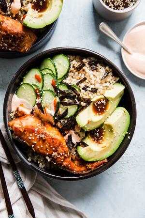 Seared garlic-ginger salmon over brown rice, avocado, cucumber, nori in a bowl.