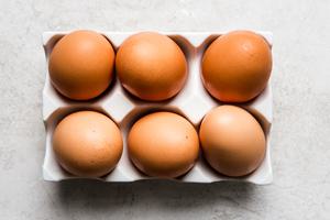 six brown eggs in a white porcelain egg holder