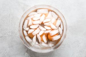 six brown eggs in a large glass bowl of ice water