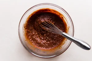 tomato past and spices mixed together with a whisk to make slow cooker butter chicken
