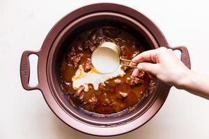 cooked slow cooker butter chicken with heavy cream being poured out of a measuring cup