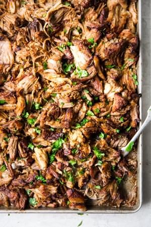 Slow Cooker Crispy Carnitas on a sheet pan with a serving spoon