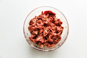 Sliced steak marinating in a bowl