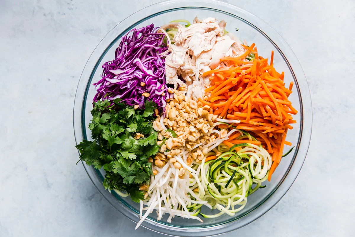carrots, purple cabbage, chicken, mung beans, zoodles, cilantro and peanuts in a large bowl
