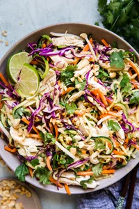 Thai Zoodle salad with chicken, peanuts, and fresh limes in a grey ceramic bowl