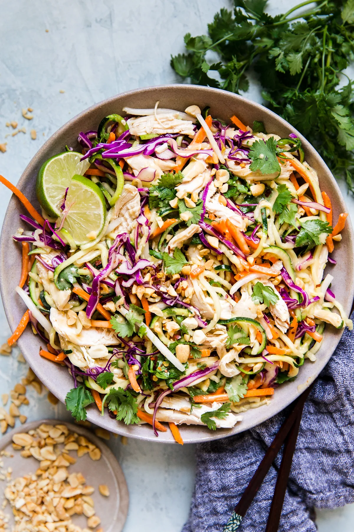 Thai Zoodle salad with chicken, peanuts, and fresh limes in a grey ceramic bowl