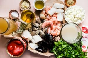 ingredients laid out for Copping with shrimp, muscles, olive oil, garlic, white fish, onions, broth, clams