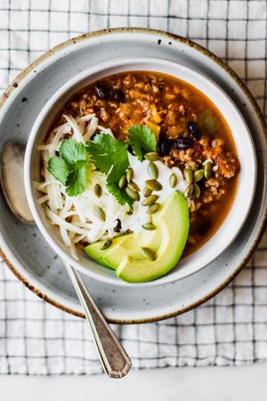 turkey pumpkin chili in a bowl on top of a plate with a spoon