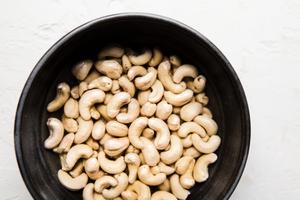 Raw cashews soaking in water in a black bowl