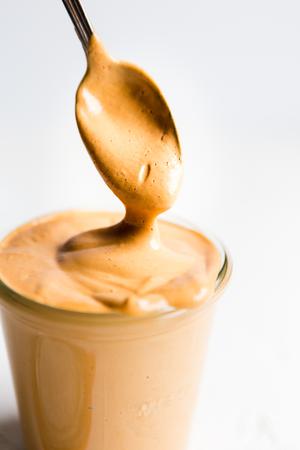 homemade Vegan Cashew Cheese Sauce in a jar with a spoon made with cashew, tomato paste, nutritional yeast and spices
