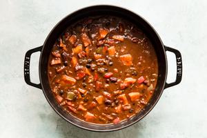 homemade vegetarian chili in a pot made with peppers, onion, sweet potatoes, beans, spices and enchilada sauce