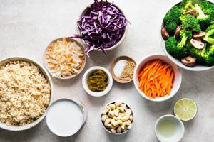 ingredients laid out, brown rice, coconut milk, coconut, green curry, cashews, carrots, red cabbage, broccoli and mushrooms